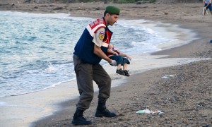 A Turkish police officer carries a young boy who drowned in a failed attempt to sail to the Greek island of Kos